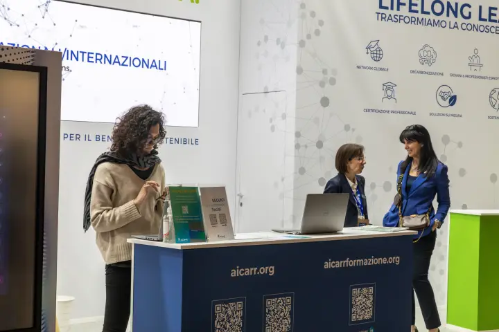AiCARR reception counter with QR codes and Lifelong Learning wall at MCE 2026