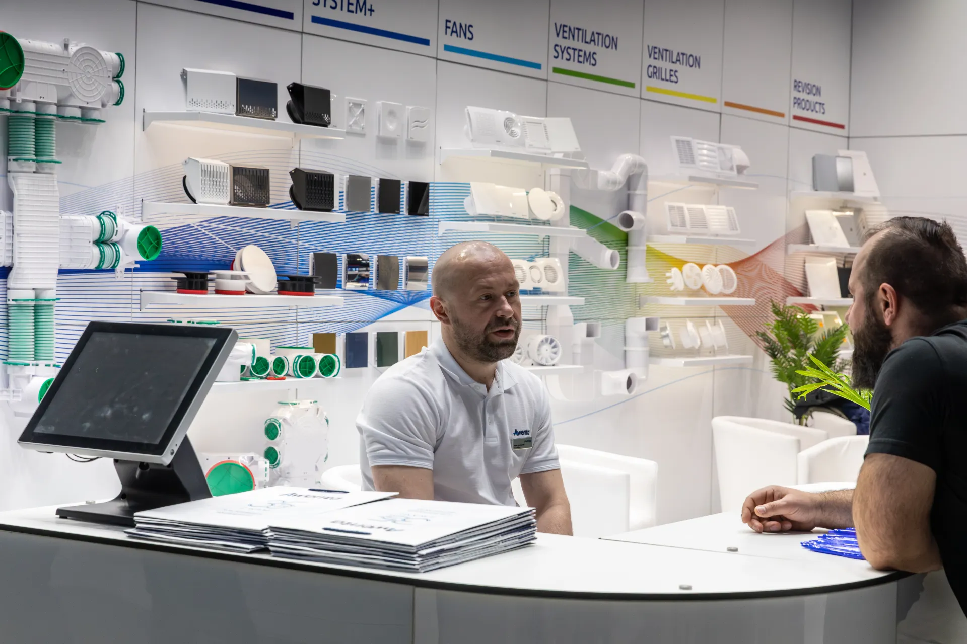 Awenta counter conversation in front of fans and grilles product wall at MCE 2026