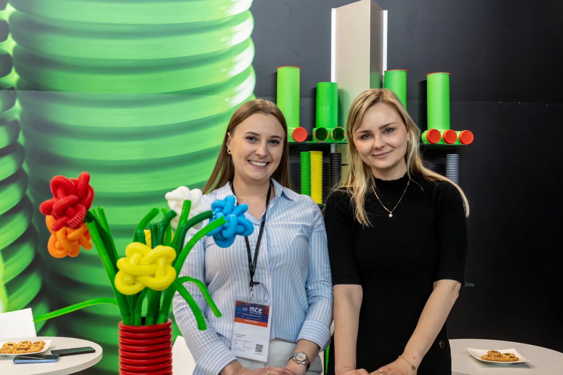 Close portrait of TT Plast staff beside green pipe samples at MCE 2026