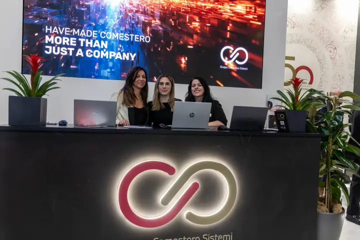 Comestero reception counter with backlit logo and 'More Than Just a Company' screen at MCE 2026