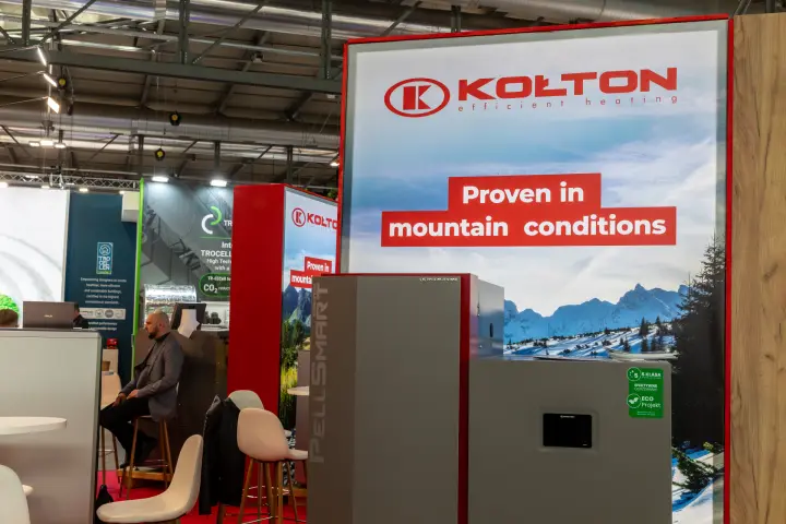 Kołton PellSmart heating unit before a backlit 'Proven in mountain conditions' panel