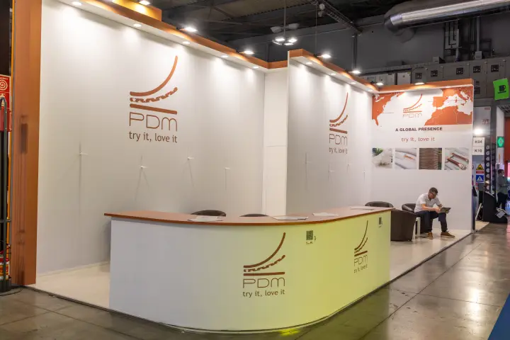 PDM stand with copper-toned branding and global presence map at MCE 2026