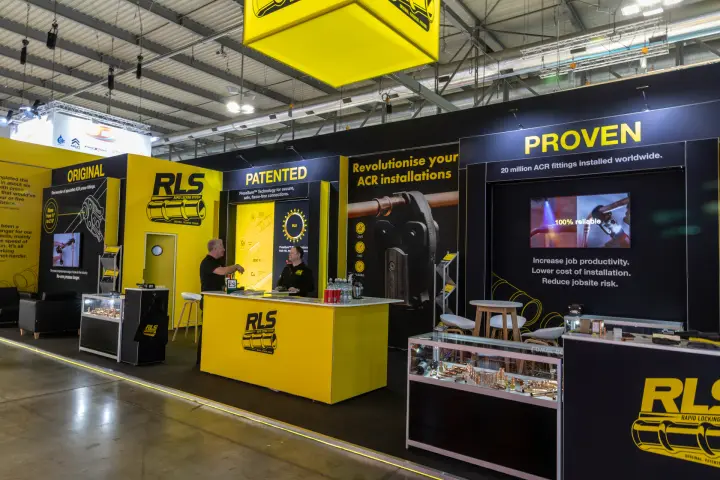RLS stand presenting press-fit ACR fittings under a yellow hanging cube at MCE 2026