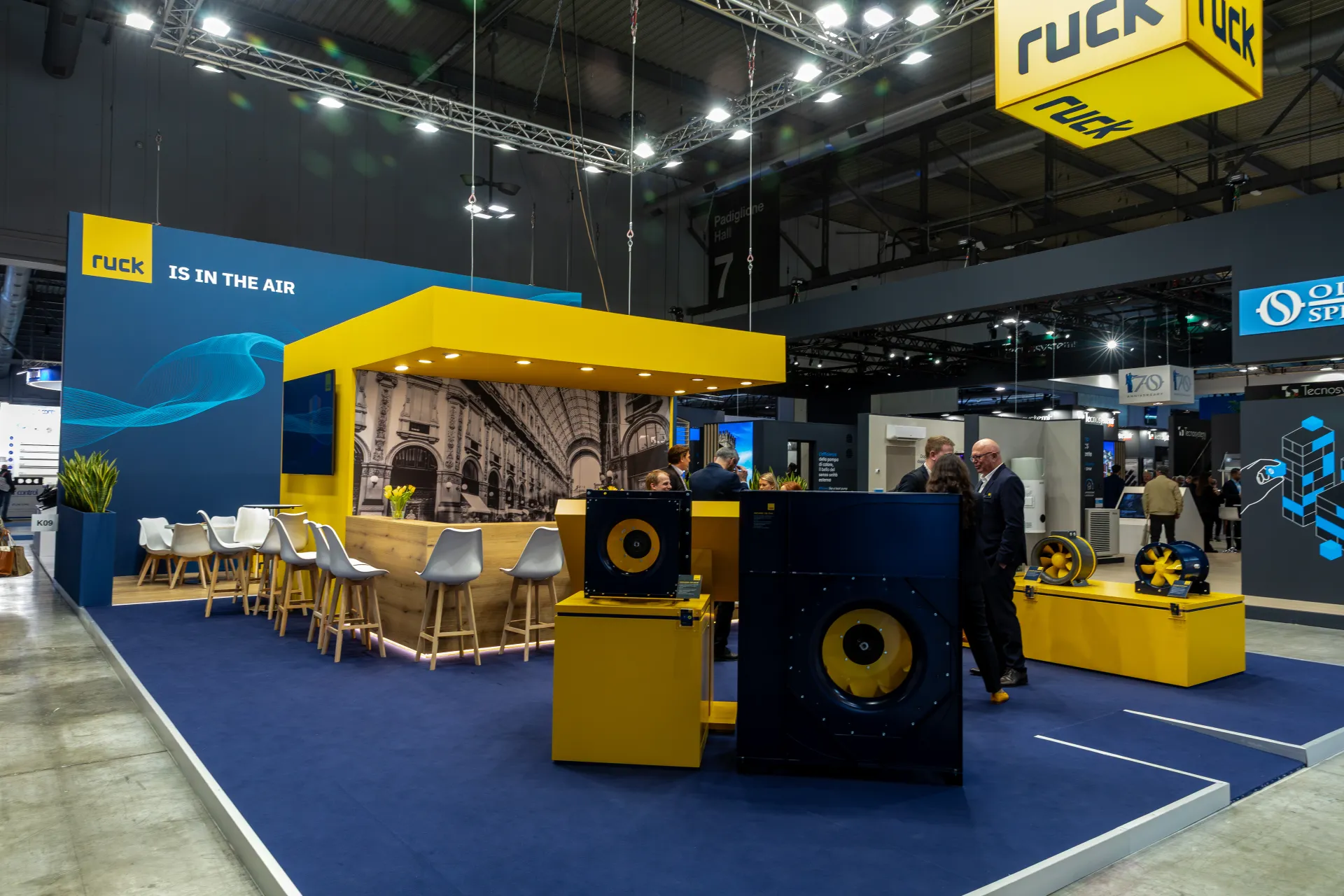 Ruck stand with yellow-canopied bar, arcade mural and plug fans at MCE 2026