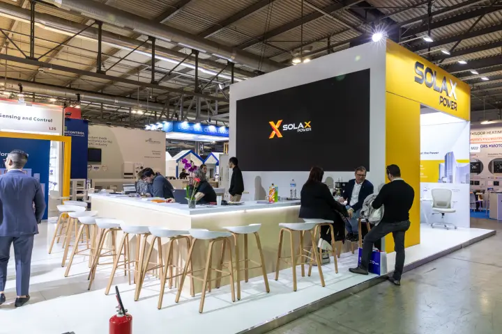 SolaX Power bar counter with wooden stools and a large logo screen