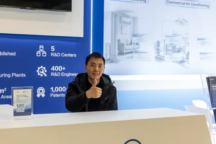 Staff member at a reception counter in front of a company-facts wall