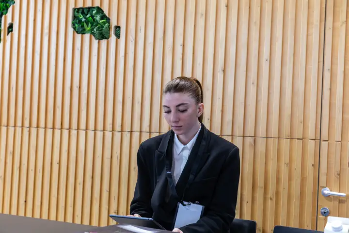 Staff member at a reception desk in front of a wood slat wall