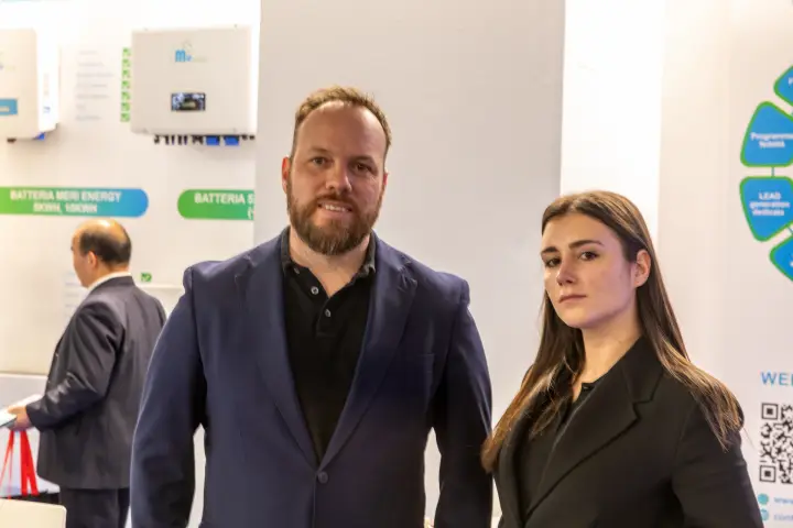 Staff portrait on the Meri Energy stand in front of inverter displays