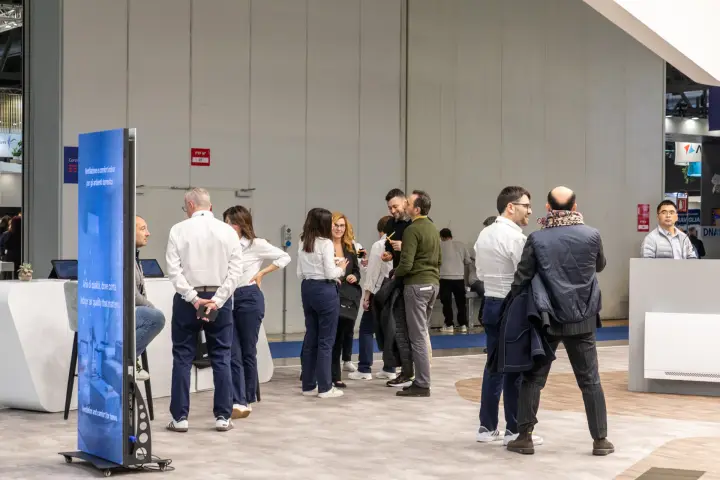 Staff and visitors gathered on an open stand beside a digital totem