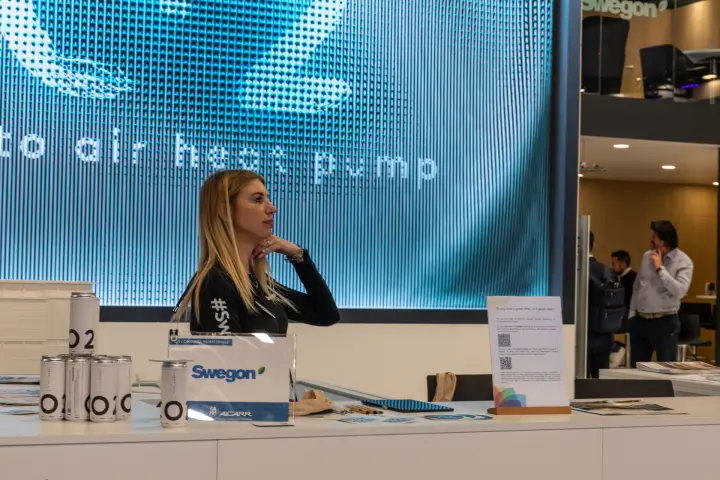 Swegon reception counter in front of an LED wall about an air heat pump at MCE 2026