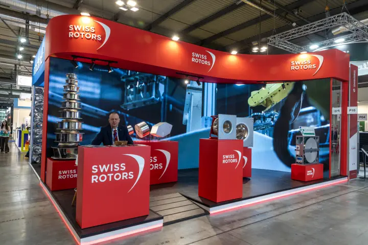 Swiss Rotors corner stand with wave-shaped red fascia and LED wall