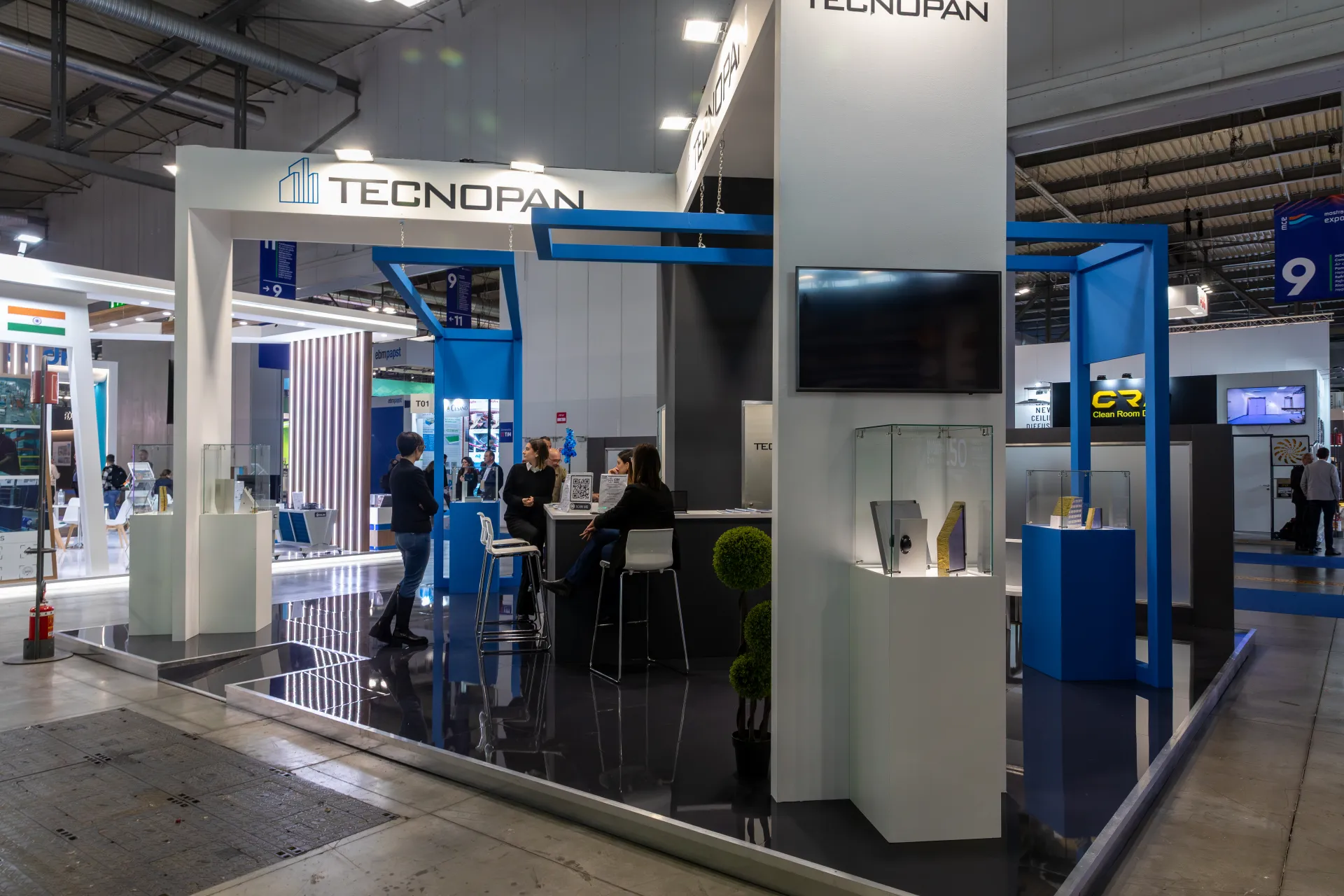 Tecnopan stand with blue frames and panel samples in glass cases at MCE 2026