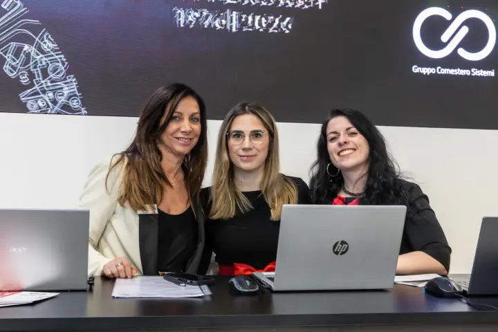 Three staff members at the Gruppo Comestero Sistemi reception desk at MCE 2026