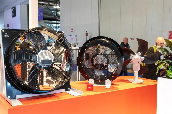 Two axial fans and an impeller with NEW and NEU tags on an orange plinth at MCE 2026