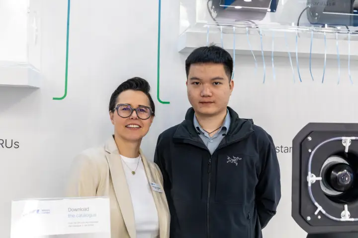 Two people beside a centrifugal fan and catalogue sign at MCE 2026