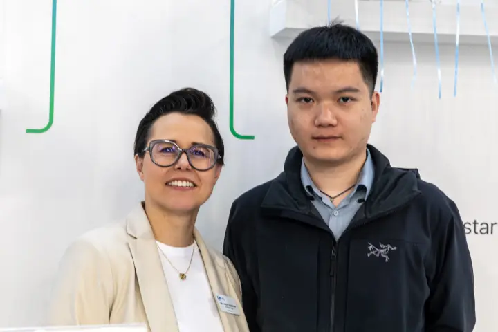 Two people posing against a white stand wall at MCE 2026