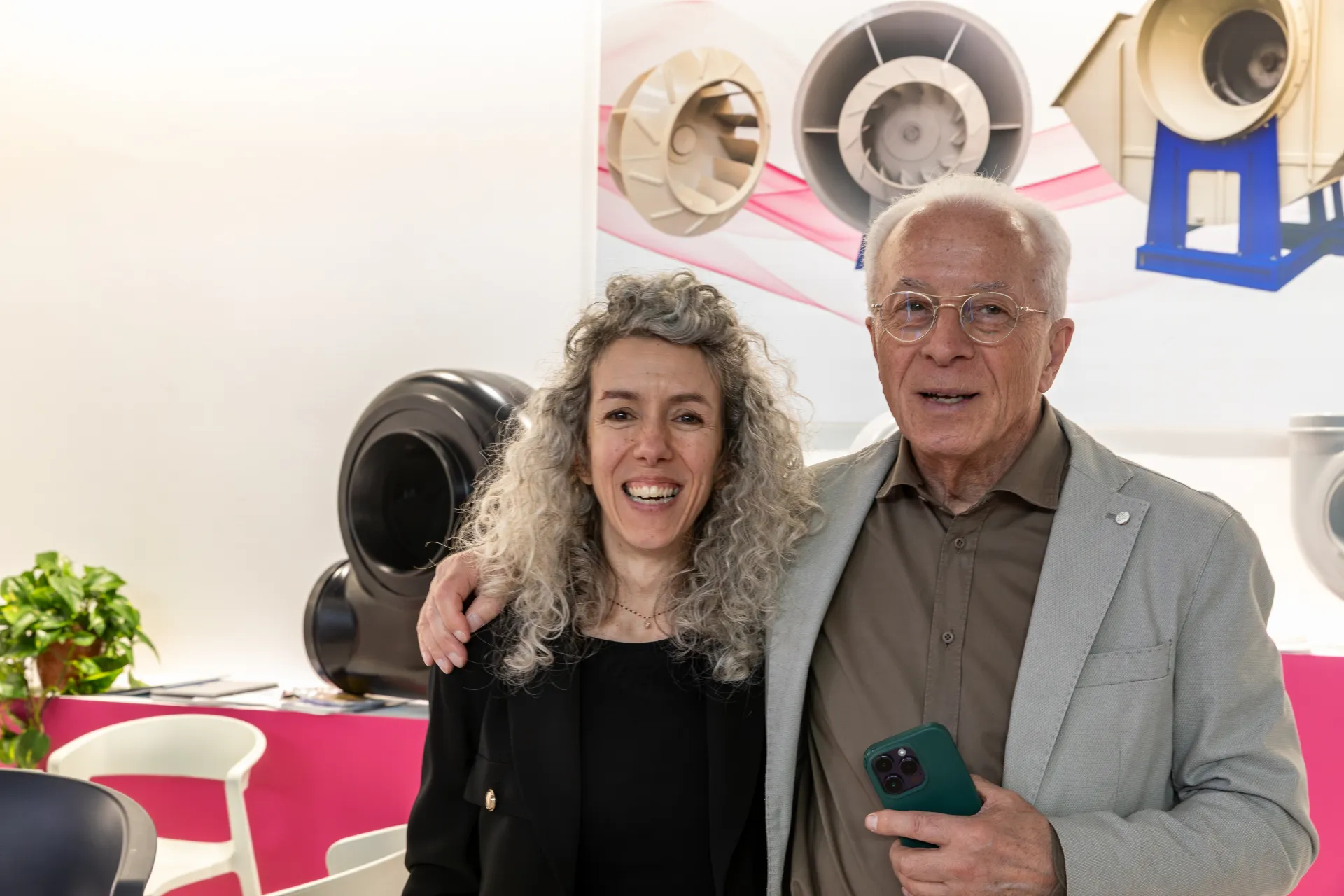 Two people posing in front of a plastic fan display at MCE 2026