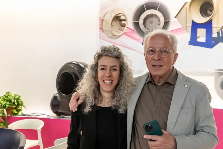 Two people posing in front of a plastic fan display at MCE 2026