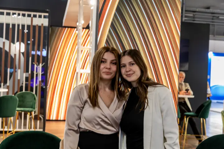 Two staff members beside a slatted screen and copper-striped panels