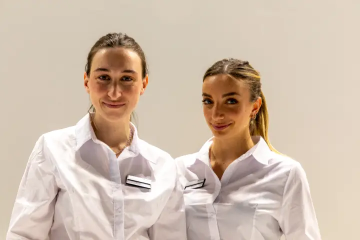 Two staff members posing in close-up against a white wall at MCE 2026