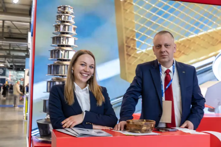 Two staff at a red counter beside the impeller tower, close portrait at MCE 2026