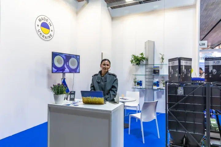 Wider view of the KVZO booth with reception desk and brochure shelves at MCE 2026