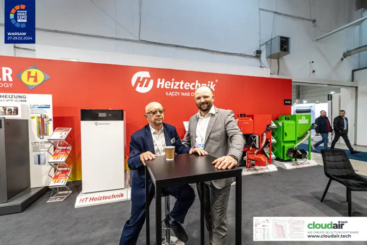 Exhibitors at a high table in front of the Heiztechnik wall and pellet boilers
