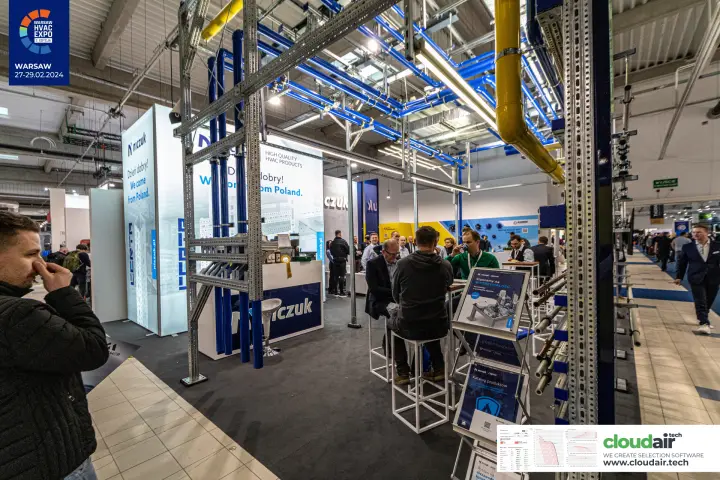 Visitors at high tables under Niczuk's suspended pipe and duct display at Warsaw HVAC Expo 2024