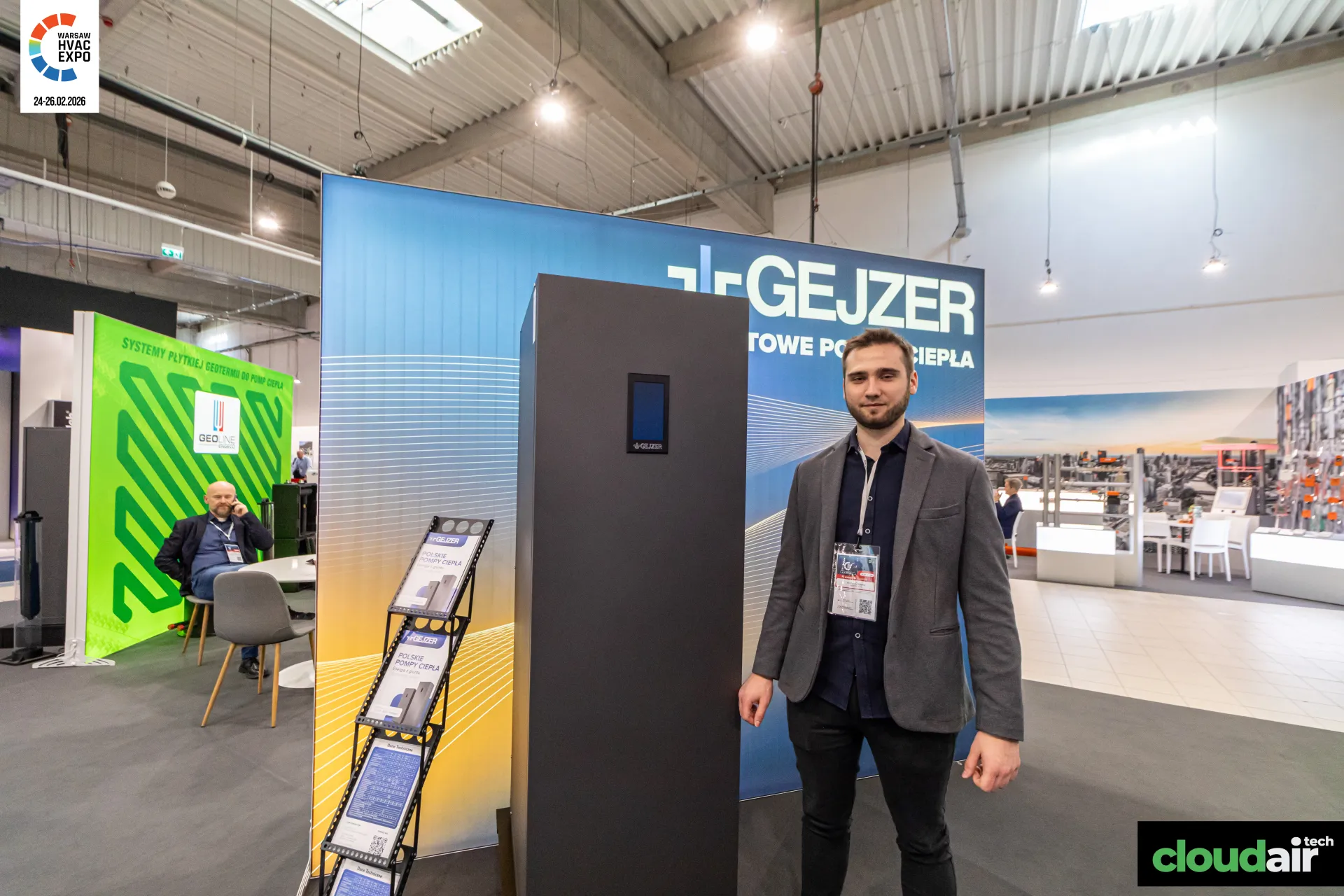 Gejzer representative beside a dark ground-source heat pump cabinet at Warsaw HVAC Expo 2026