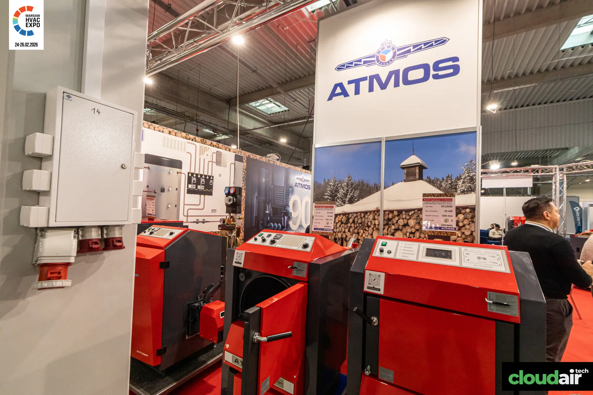 Red Atmos wood boilers, one with its loading door open, under the brand tower at Warsaw HVAC Expo 2026