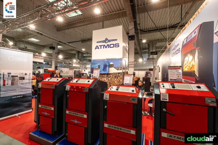 Row of red Atmos wood boilers beside a Debe Laddomat roll-up at Warsaw HVAC Expo 2026